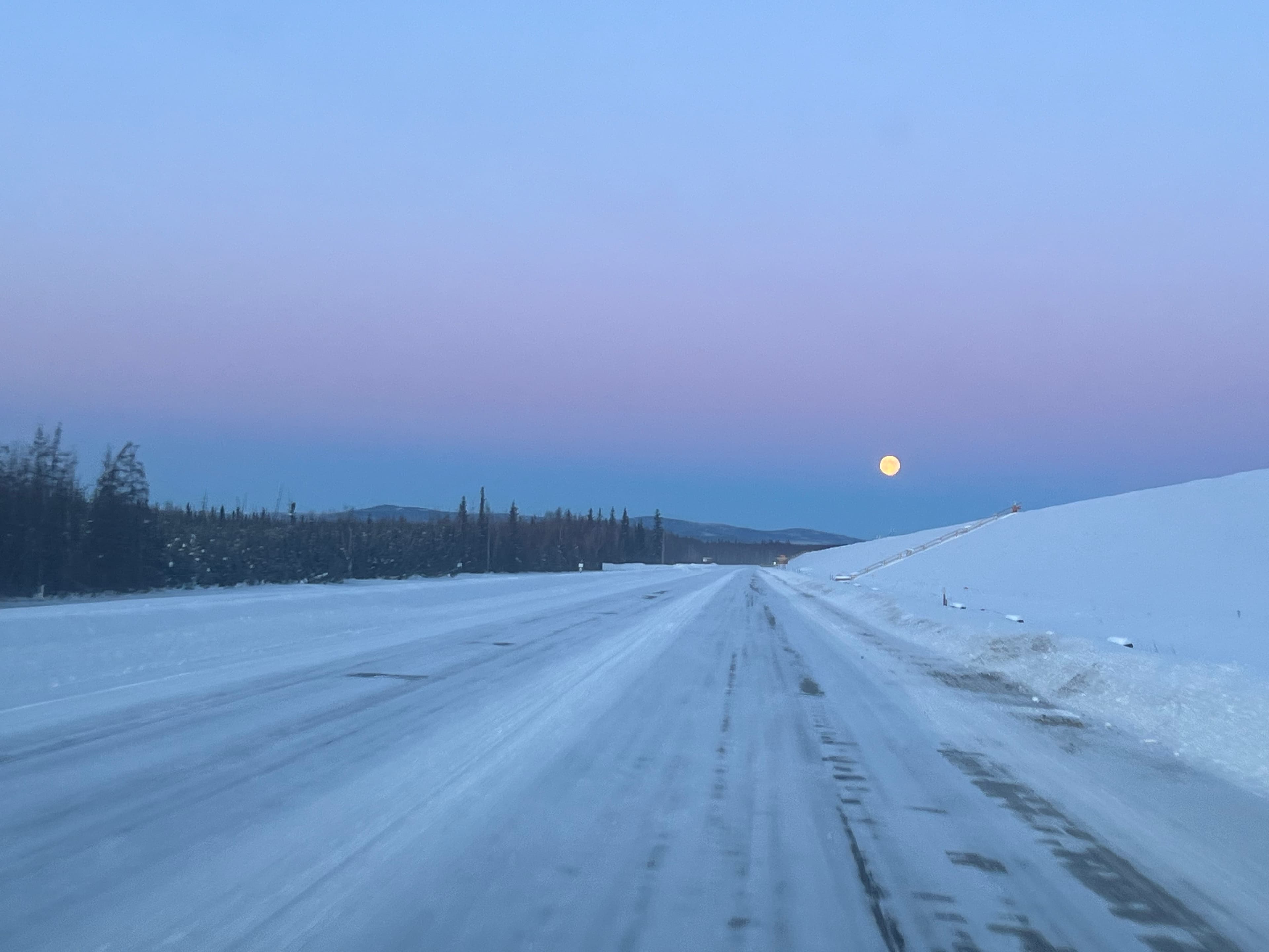 Snowy road under a pink sky in Alaska